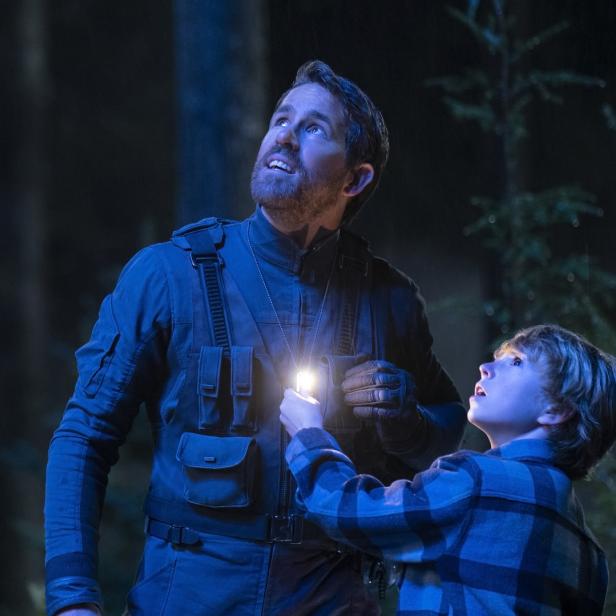 Ryan Reynolds und ein Kind leuchten mit einer Taschenlampe in den Nachthimmel.