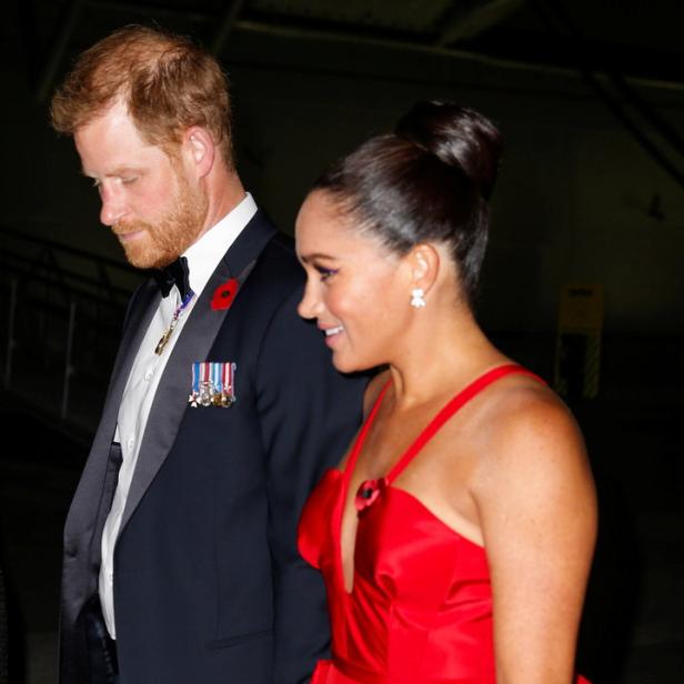 Prinz Harry und Meghan Markle bei einer Veranstaltung, sie trägt ein rotes Kleid.
