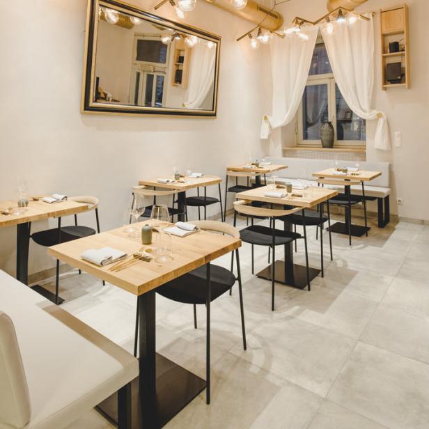 Ein modern eingerichtetes Restaurant mit Tischen und auffälliger Beleuchtung.