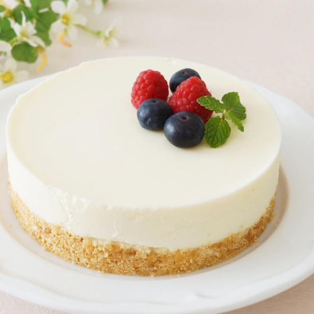 Ein Käsekuchen ist mit Blaubeeren, Himbeeren und Minze garniert.