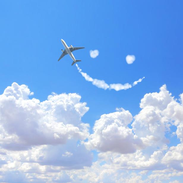 Ein Flugzeug zieht eine Rauchspur in Form eines Smileys in den blauen Himmel.