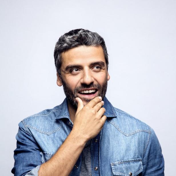 Oscar Isaac lächelt und blickt nachdenklich zur Seite.