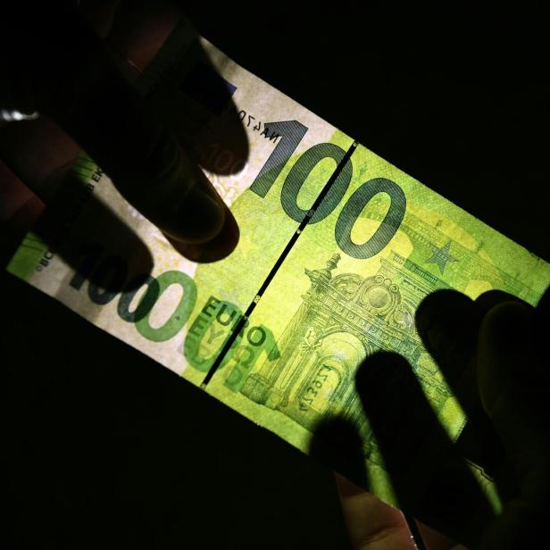 Ein 100 Euro-Schein der gegen das Licht gehalten wird.