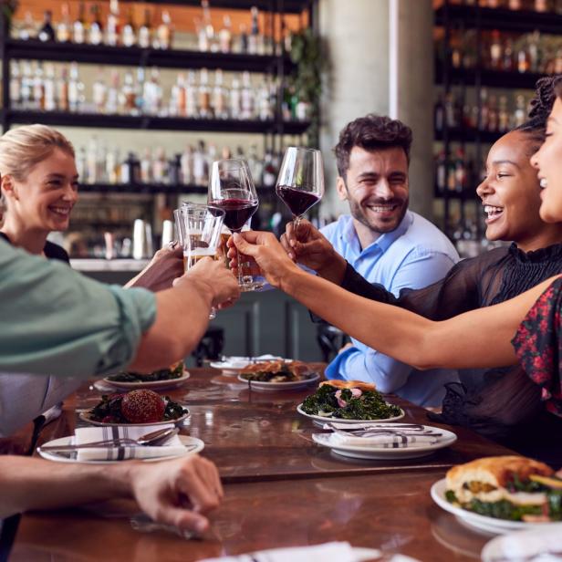 Eine Gruppe von Freunden stößt in einem Restaurant mit Wein- und Biergläsern an.
