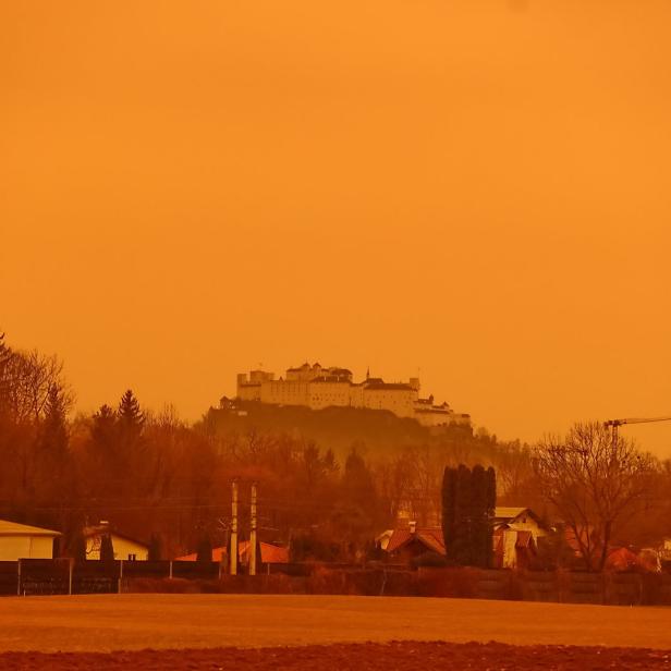 Die Festung Hohensalzburg überragt eine Landschaft in orangefarbenem Licht.