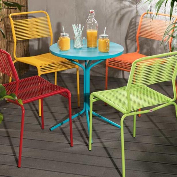 Ein Gartentisch mit Getränken, umgeben von farbenfrohen Stühlen auf einer Terrasse.