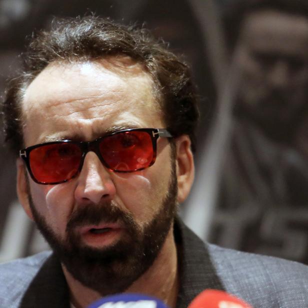 Nicolas Cage mit roter Sonnenbrille bei einer Pressekonferenz.