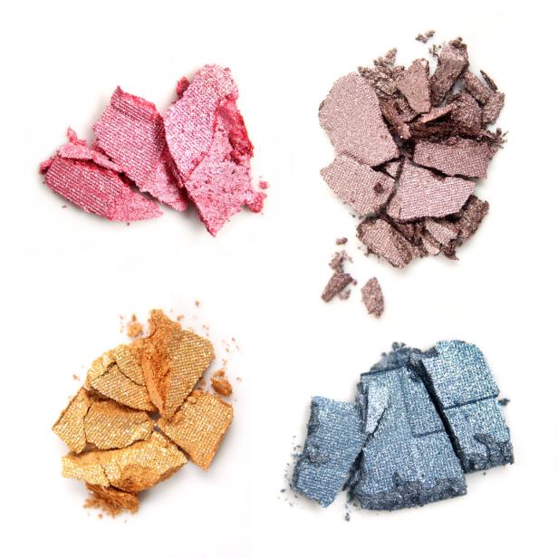 Zerkleinerte Lidschatten in Rosa, Braun, Gold und Blau auf weißem Grund.
