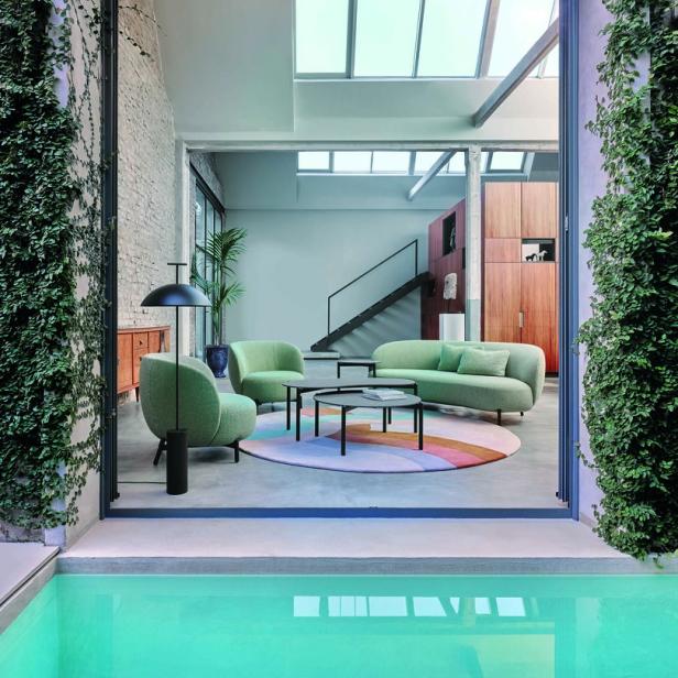 Ein Wohnzimmer mit mintgrünen Möbeln, das sich zu einem Pool öffnet.