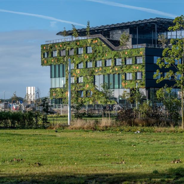 Ein modernes Bürogebäude mit einer Fassade aus Pflanzen und Bäumen.