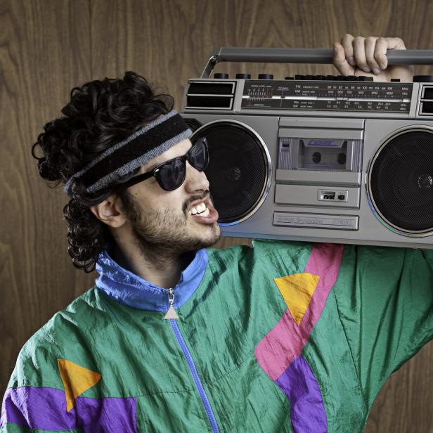 Ein Mann im 80er-Jahre-Stil trägt einen Ghettoblaster auf der Schulter.