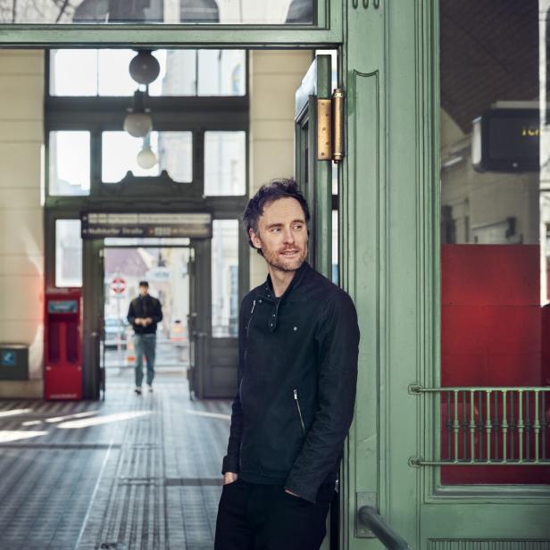 Ein Mann steht in der Tür einer U-Bahn-Station und blickt nach rechts.