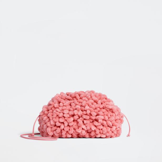 Eine rosafarbene, flauschige Handtasche mit Kordelzug vor einem weißen Hintergrund.
