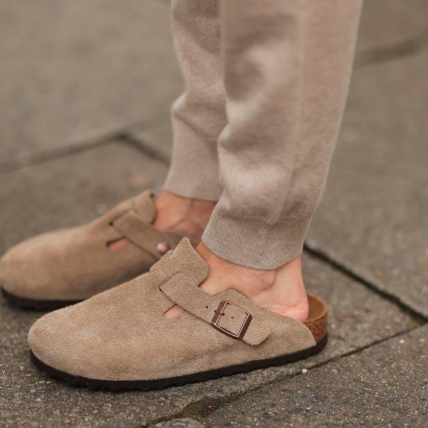 Nahaufnahme von beigen Birkenstock Clogs an den Füßen einer Person.