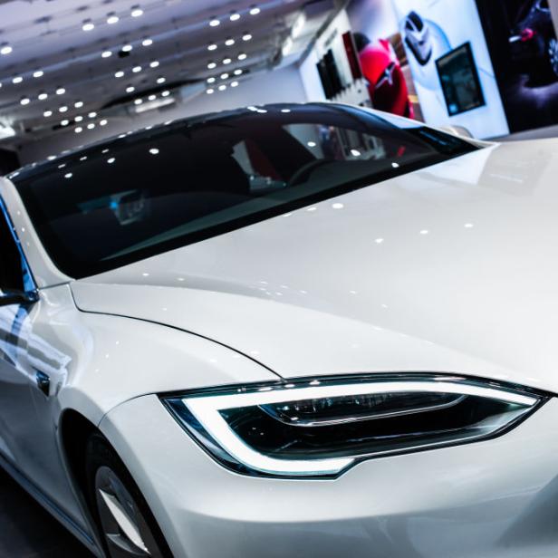 Nahaufnahme eines weißen Tesla-Autos in einem Ausstellungsraum.