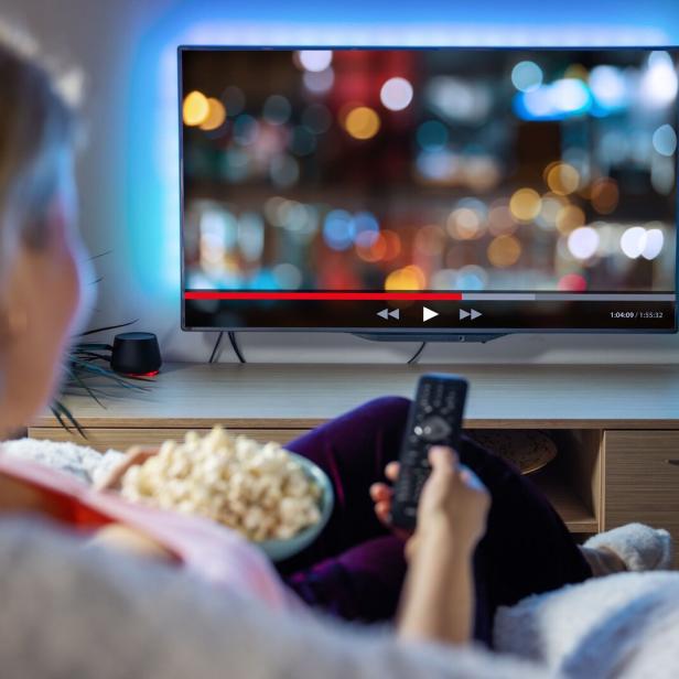 Woman relaxing at home in evening and watching TV