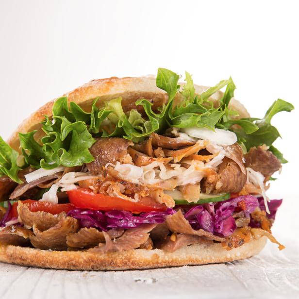 Ein Döner Kebab gefüllt mit Fleisch, Salat, Tomaten, Gurken und Kraut.