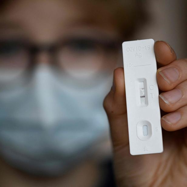 Eine Frau hält einen Corona-Schnelltest hoch.