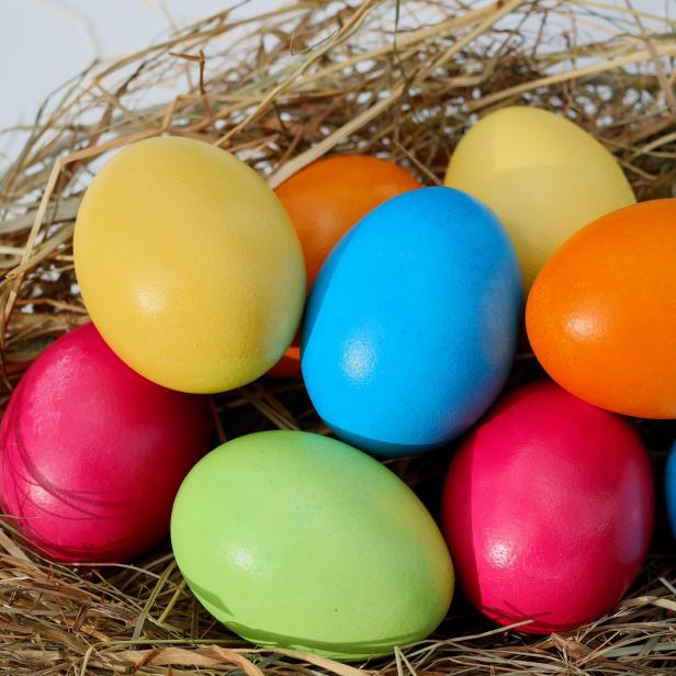 Ein Nest mit bunten Ostereiern in Gelb, Blau, Orange, Grün und Pink.