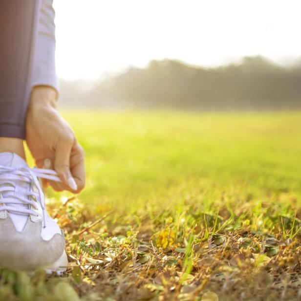 Frau schnürt die Schuhbänder der Laufschuhe.