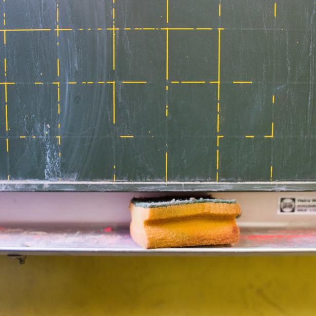 Ein Schwamm liegt auf der Ablage vor einer grünen Tafel mit gelbem Raster.