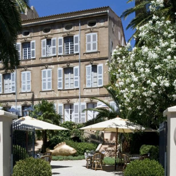 Das „La Galerie Dior“ in Grasse mit Tischen und Sonnenschirmen im Garten.