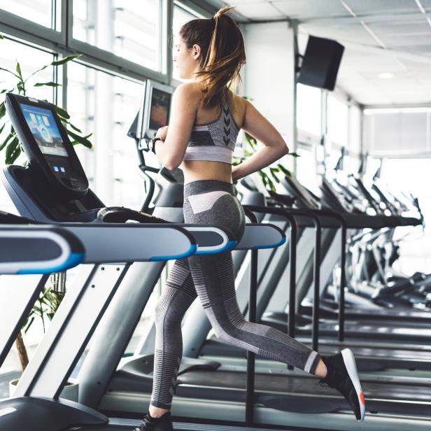Eine Frau trainiert auf einem Laufband in einem Fitnessstudio.