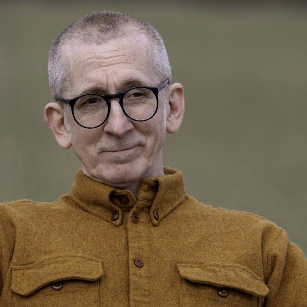 Ein Mann mit Brille und braunem Hemd blickt in die Ferne.