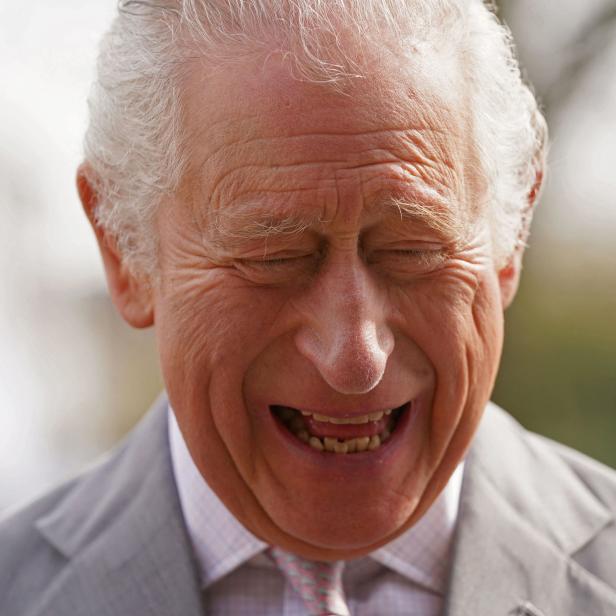 König Charles lacht mit geschlossenen Augen.