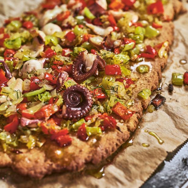 Eine Tarte mit Gemüse und kleinen Oktopussen belegt.