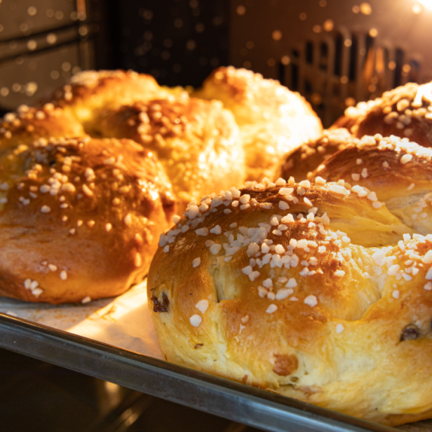 Ein Blech mit mehreren, mit Hagelzucker bestreuten Hefezöpfen im Ofen.