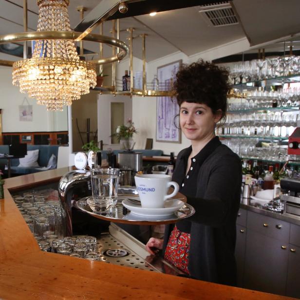 Eine Kellnerin serviert eine Tasse Kaffee in einem Wiener Caféhaus.