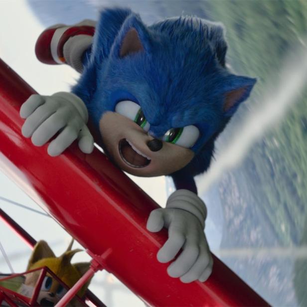 Sonic the Hedgehog hängt an einem roten Doppeldecker, während Tails das Flugzeug steuert.
