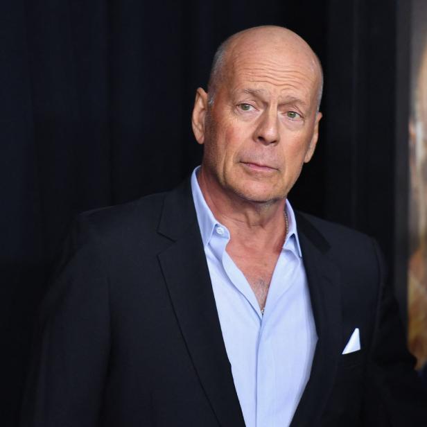 Bruce Willis posiert in einem schwarzen Anzug auf einem Event.