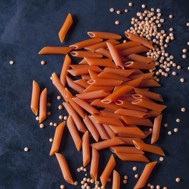Rote Linsenpasta und lose Linsen auf dunklem Untergrund.