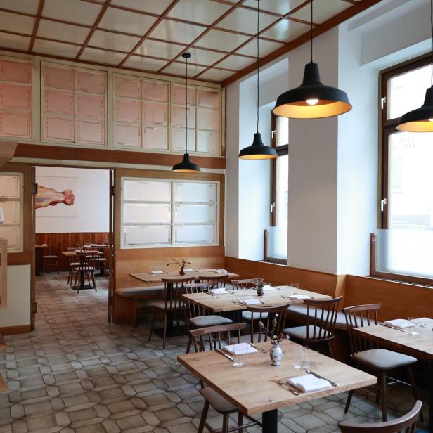 Innenansicht eines einladenden Restaurants mit Holztischen und Stühlen.