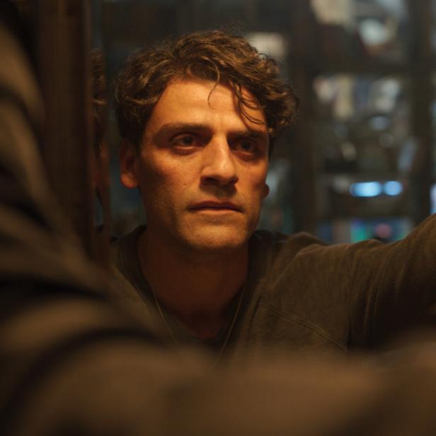 Oscar Isaac blickt in einem dunklen Raum in einen Spiegel.