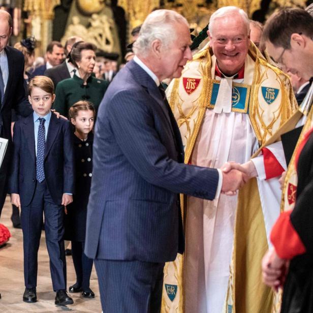 König Charles schüttelt einem Geistlichen die Hand, während Prinz William, Prinz George und Prinzessin Charlotte zusehen.