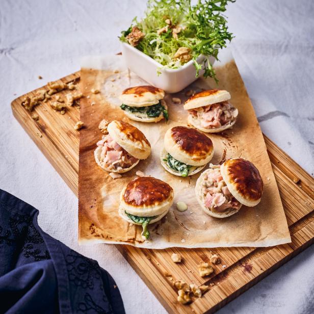 Verschiedene Canapés und ein kleiner Salat auf einem Holzbrett angerichtet.