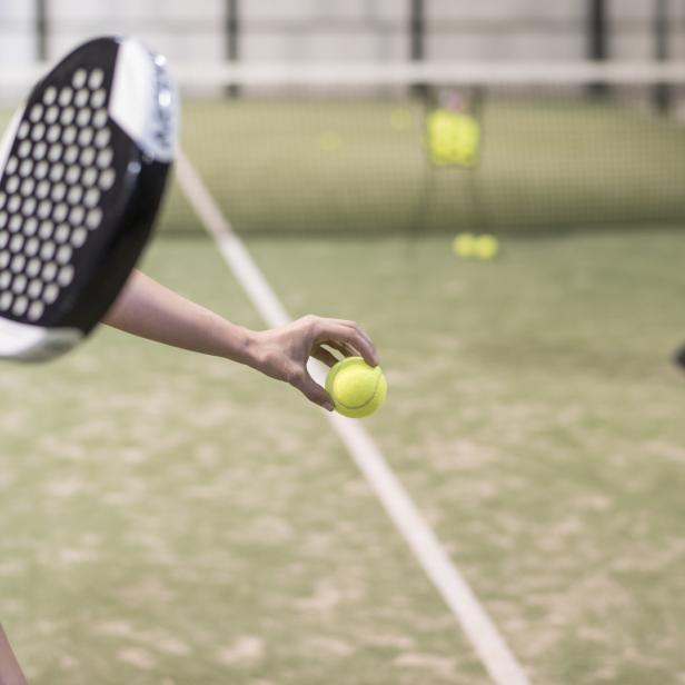 Eine Frau bereitet sich auf einem Padel-Platz vor, den Ball zu servieren.