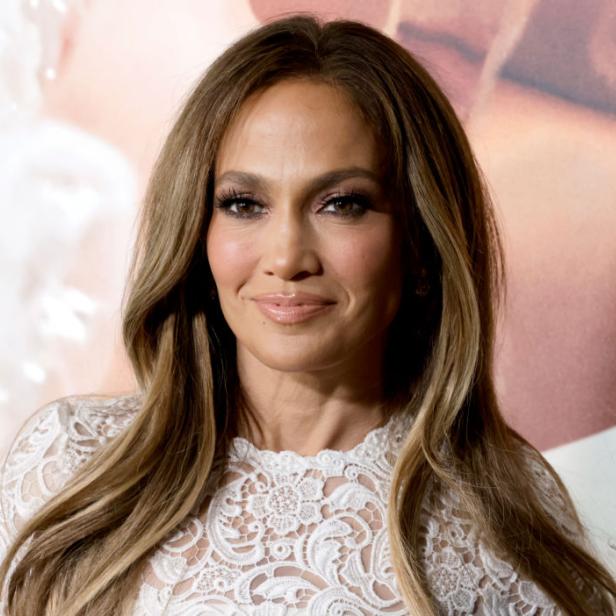 Porträt von Jennifer Lopez mit blonden Haaren und einem weißen Spitzenkleid.