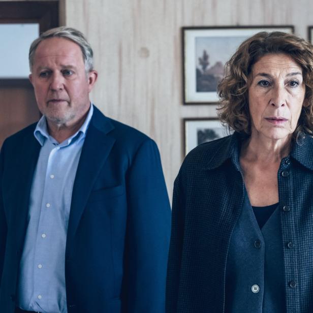 Ein Mann im Anzug und eine Frau in einer Jacke stehen nebeneinander.