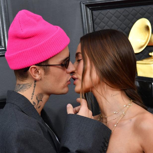 Justin und Hailey Bieber küssen sich vor einer goldenen Grammy-Trophäe.