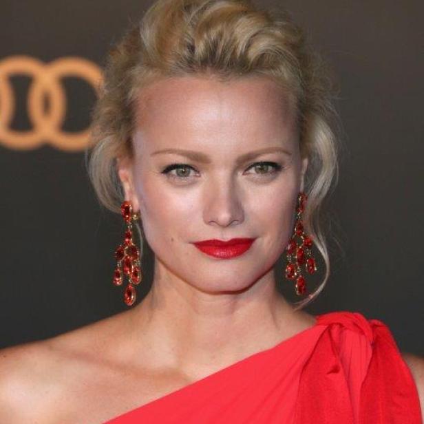 Malin Åkerman trägt ein rotes Kleid und rote Ohrringe.