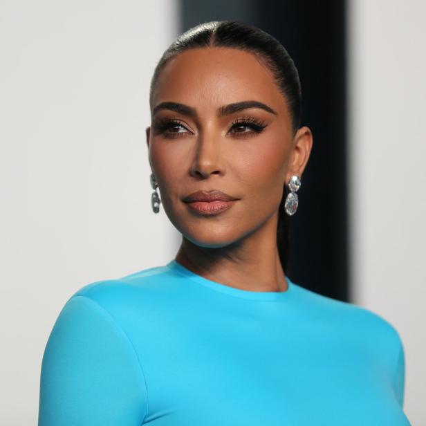 Kim Kardashian trägt ein hellblaues Kleid und auffällige Ohrringe.
