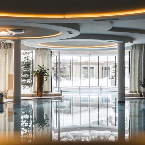 Ein Innenpool mit großen Fenstern und reflektierendem Wasser.
