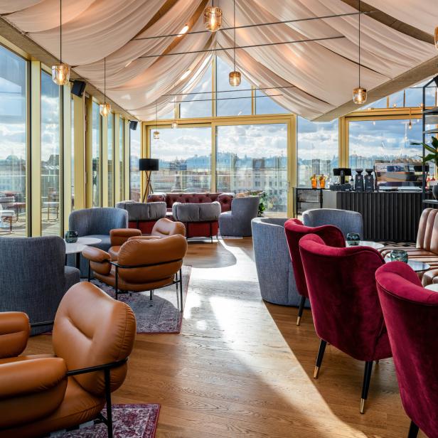 Ein luxuriöser Loungebereich mit Sesseln und Sofas unter einem Baldachin mit Blick auf die Stadt.