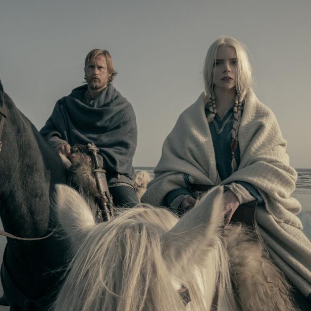 Anya Taylor-Joy und Alexander Skarsgård reiten in „The Northman“ auf Pferden am Strand.