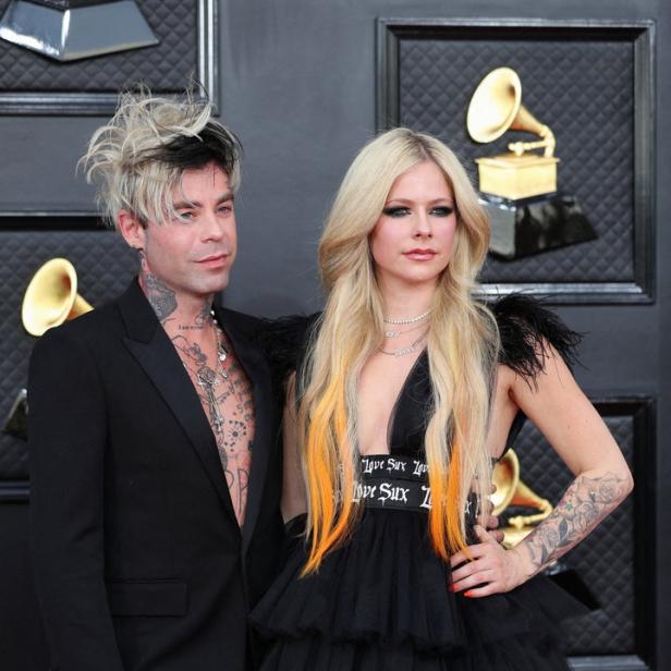 Avril Lavigne und Mod Sun posieren auf dem roten Teppich.