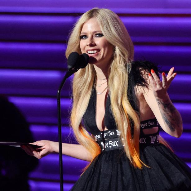 Avril Lavigne spricht bei einer Veranstaltung in ein Mikrofon.